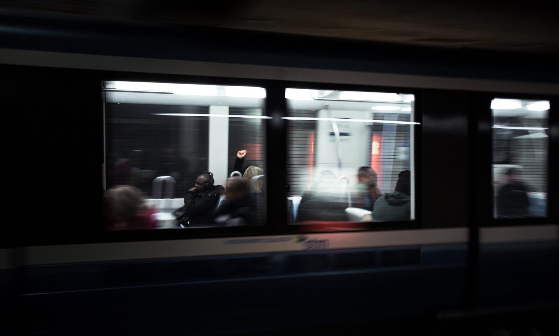 Vue d’un métro en mouvement, capturant des passagers à travers les vitres avec un effet de flou dynamique.