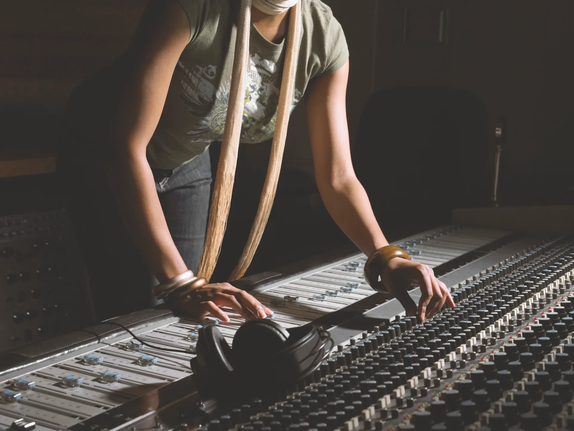 Ingénieure du son ajustant une table de mixage dans un studio d'enregistrement.