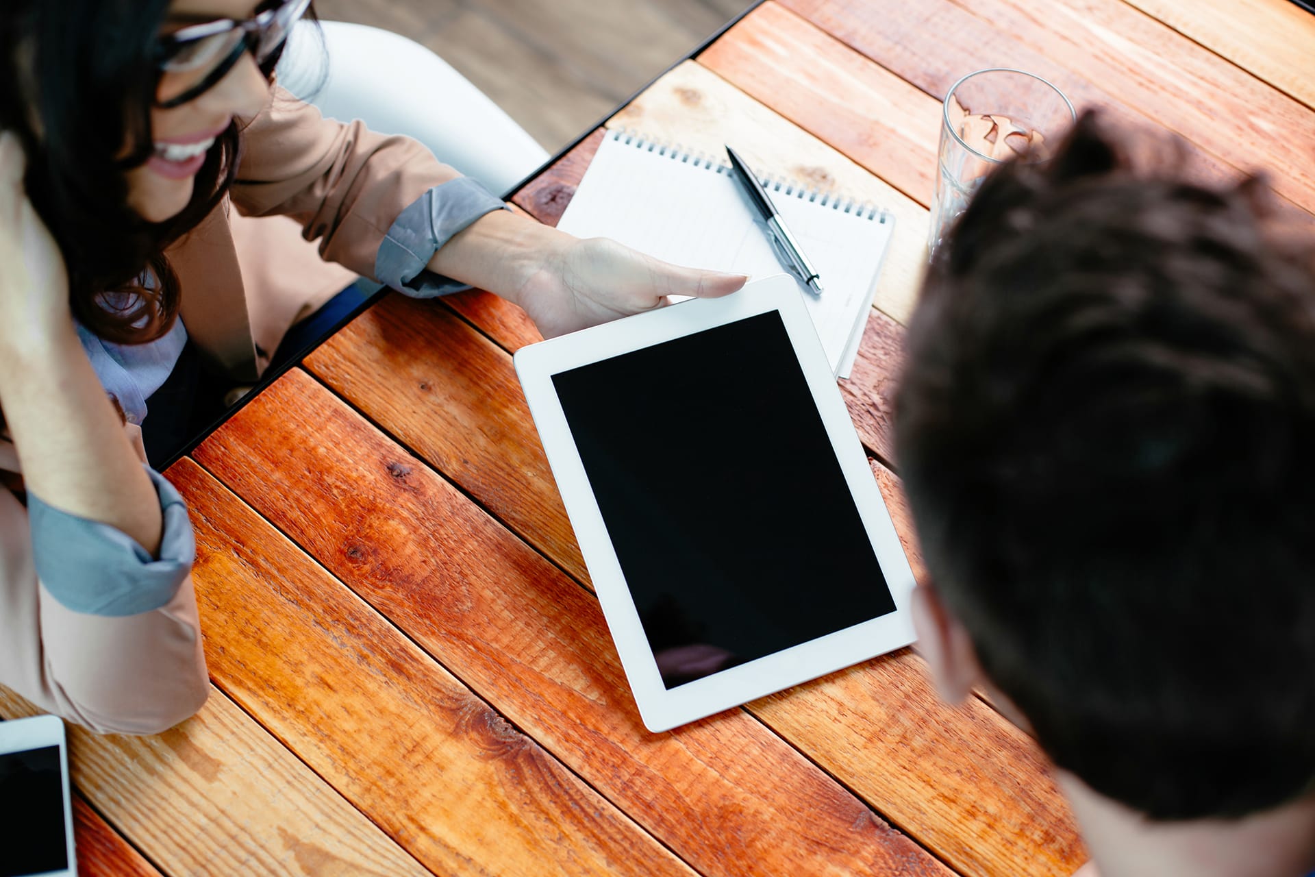 Deux collègues en réunion, utilisant une tablette numérique sur une table en bois.