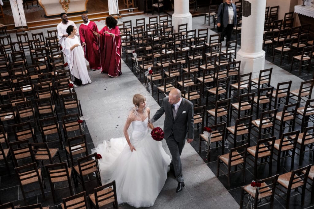 Invités assistant à une cérémonie de mariage religieux dans une église gothique avec vitraux et architecture imposante.