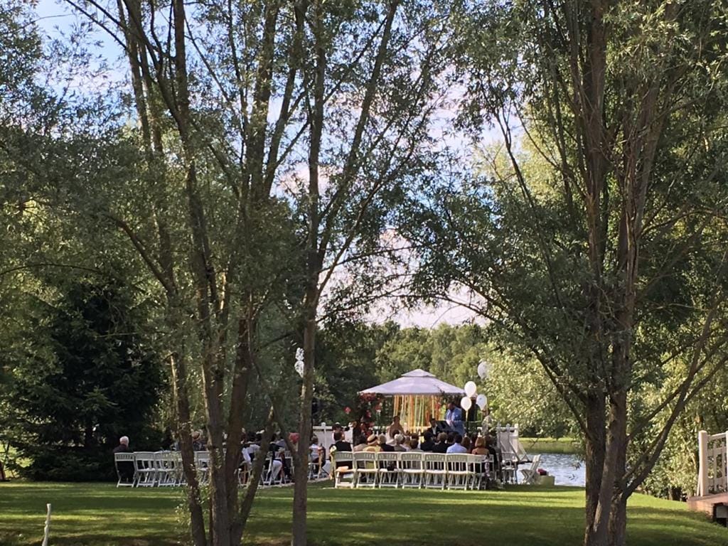 Cérémonie de mariage en plein air au bord d'un lac, entourée de nature et d'arbres.