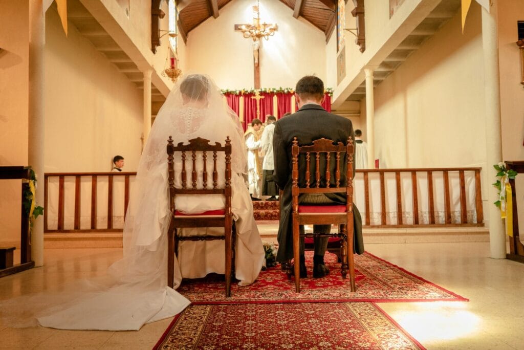 Vue d’ensemble d’une église richement décorée où se déroule une cérémonie de mariage, avec une chorale gospel en robes rouges chantant près de l’autel et une assemblée réunie dans les bancs.