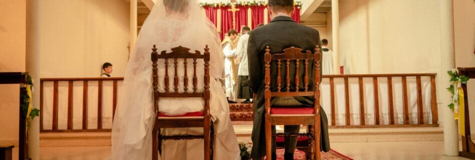 Un couple de mariés assis devant l'autel lors d'une cérémonie de mariage religieuse dans une église.