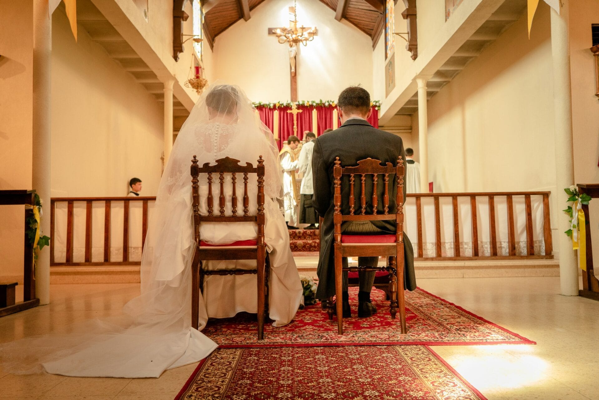 Un couple de mariés assis devant l'autel lors d'une cérémonie de mariage religieuse dans une église.